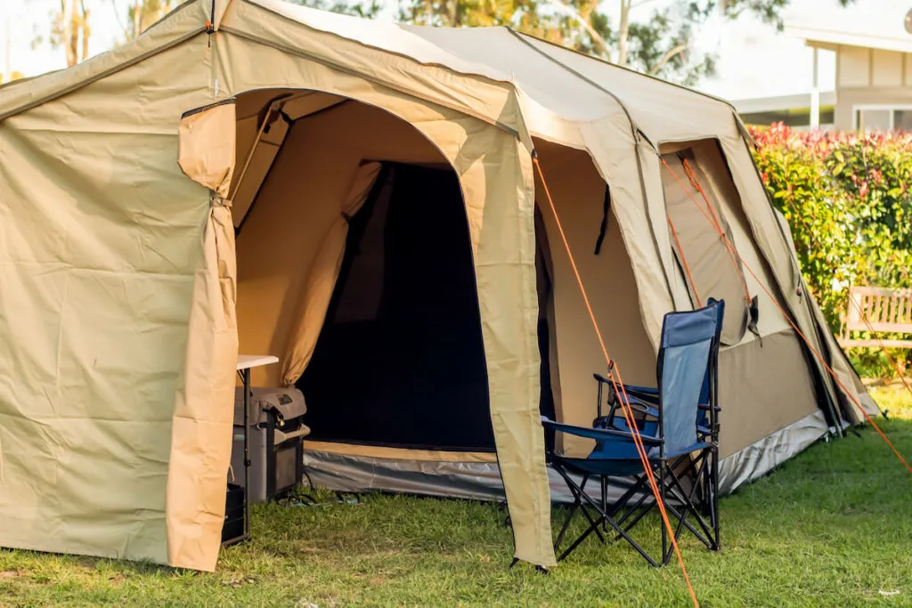 Large spacious tent setup with chairs, table and camping fridge at the campsite 