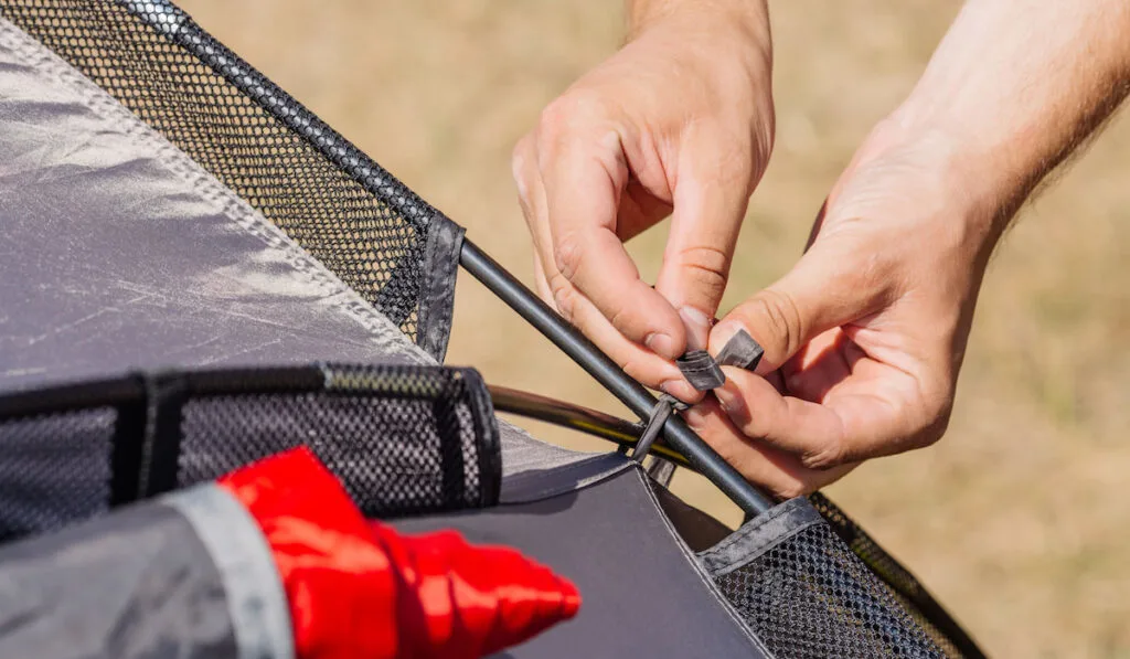 Man Tied the tent rope with on tent pole 