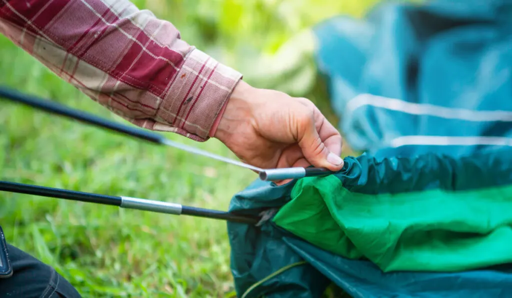 close-up of the hand of a man who packing up a tent 