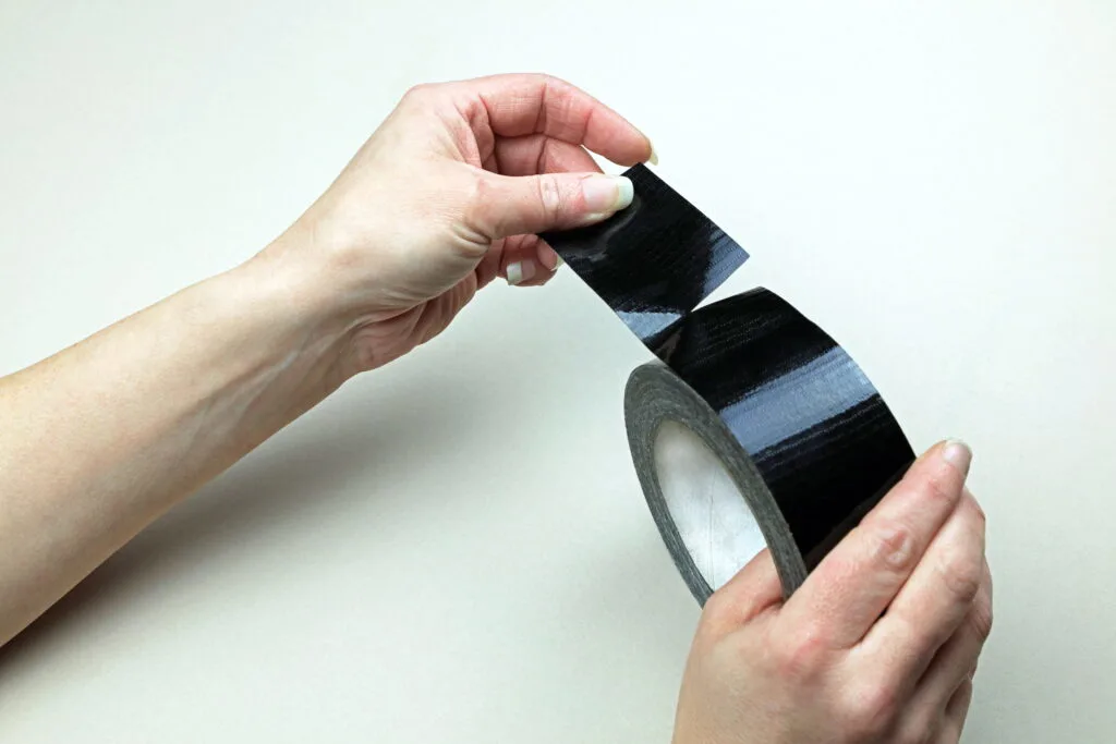 A Hand Ripping Off A Piece Of Industrial Adhesive Tape From A Roll