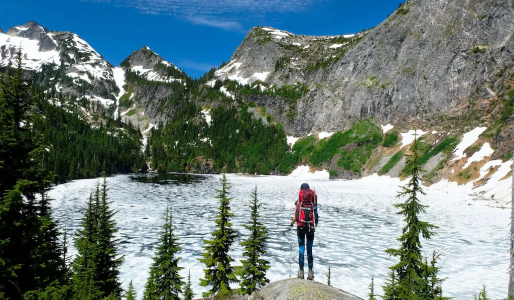 A Woman Hiker Looking at Frozen Thorton Lake and Trappers Peak. North Cascades National Park, Washington 