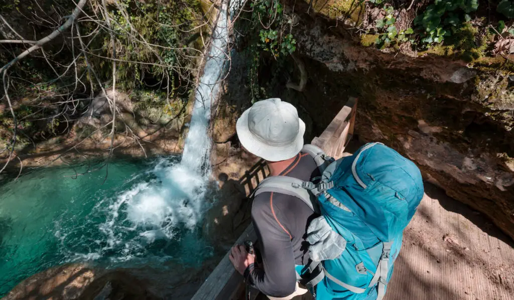 Backpacker looking at the waterfall in green spring forest