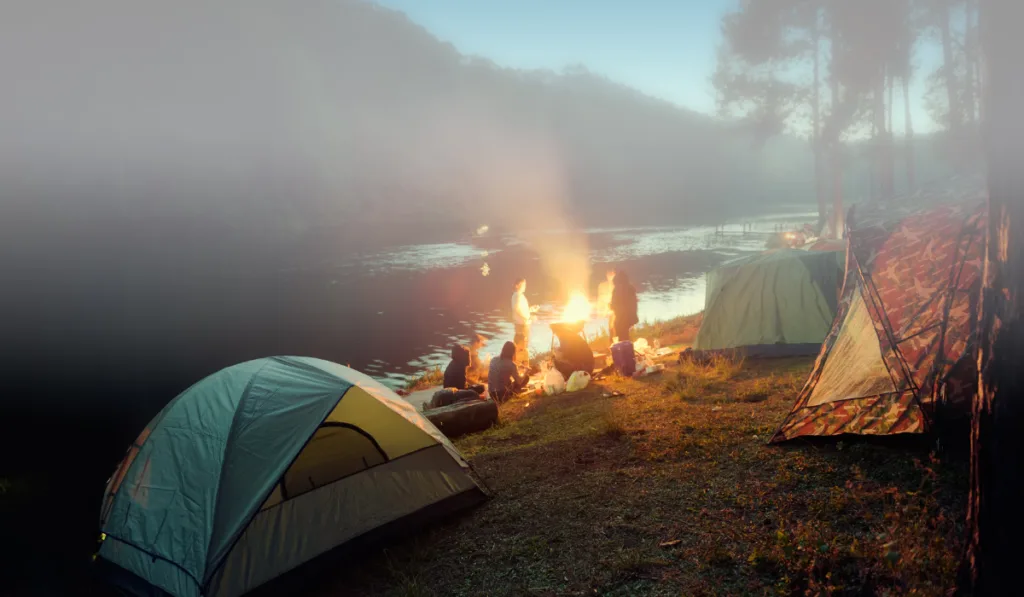 Camping tent with blured image group of backpackers relaxing near campfire