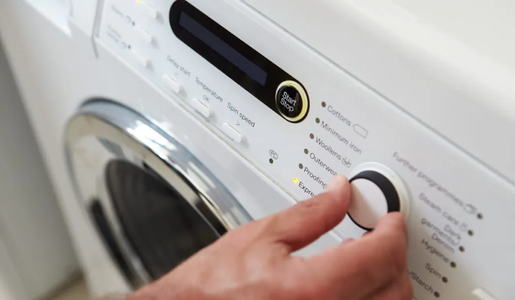 Close Up Of Man Choosing Cycle Program On Washing Machine