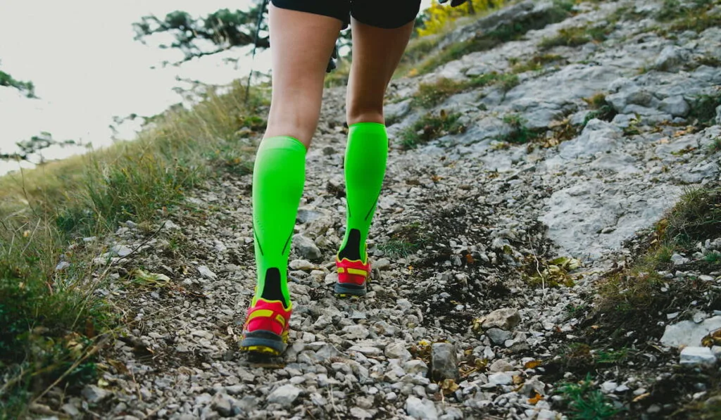 Closeup slender and beautiful legs of girl running uphill on track in compression socks