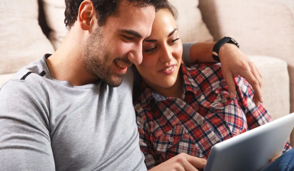 Couple sitting in the living room and using tablet for researching 