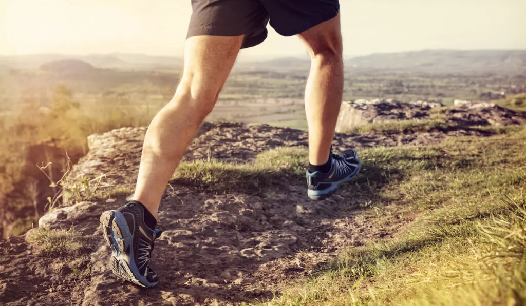 Cropped shot of a hiker running on a trail focus on trail running shoes 