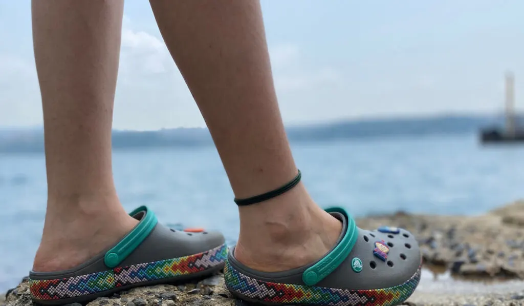 Cropped shot of a man wearing crocs near the beach area 