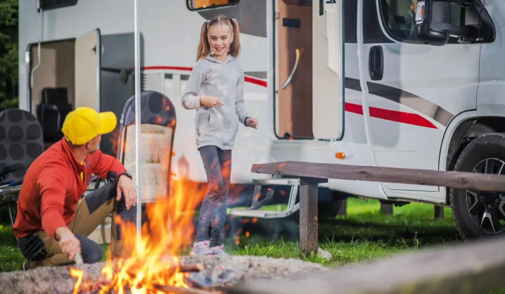 Father with Daughter Having Fun in Front of Campfire on a campsite