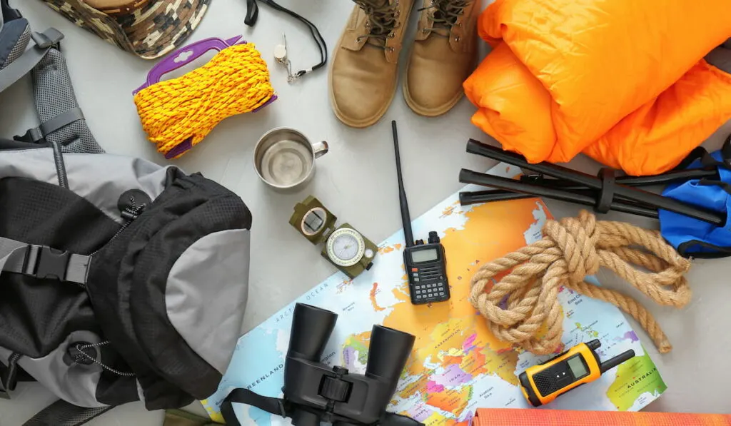 Flat lay composition with sleeping bag and camping equipment on grey background