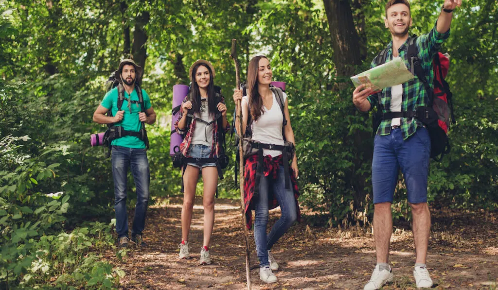 Friends camping together, man showing direction using map