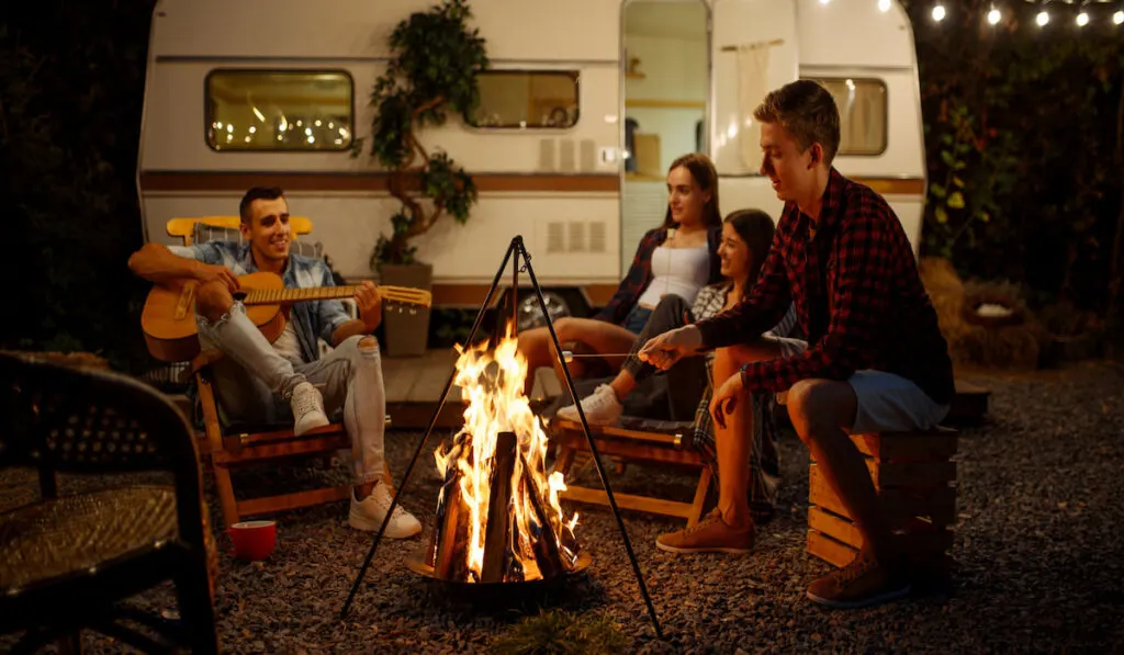 Friends playing on guitar by the campfire, camping