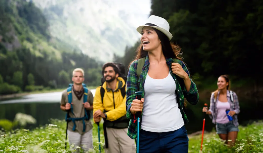 Group of smiling friends hiking with backpacks outdoors.