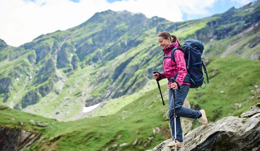 Hiker woman with a backpack walking down on the rocky terrain