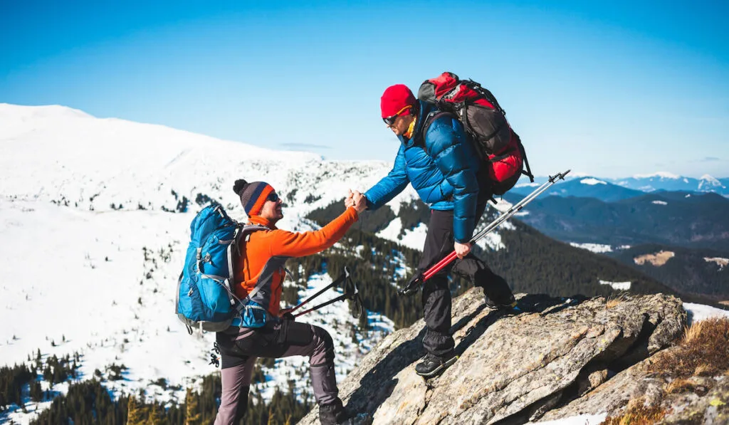 Hikers helping his friend climb 