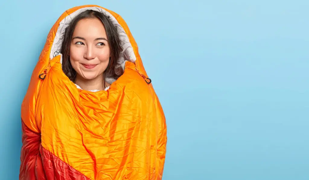 Image of attractive dark haired girl rests in sleeping bag