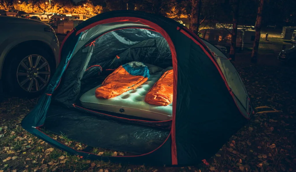 Inside Illuminated Tent on the Campsite at Night with Two Sleeping Bags Inside