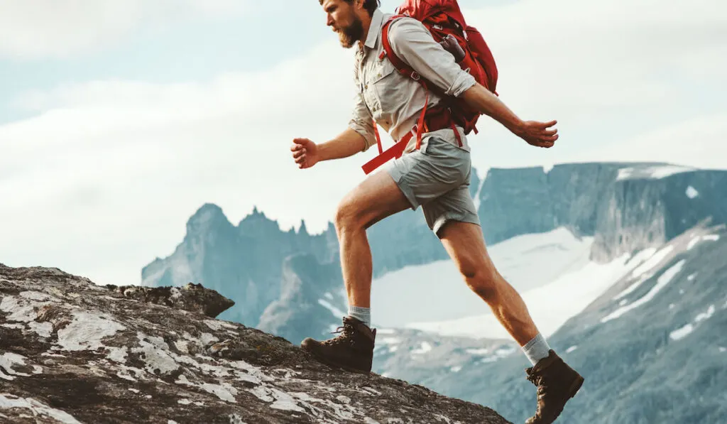 Man skyrunning in mountains with backpack and wearing hiking boots, travel hiking concept
