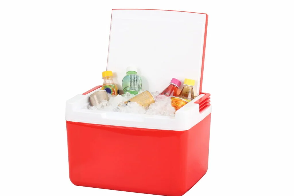 Opened red cooling box with bottles of beverage and ice isolated on white background
