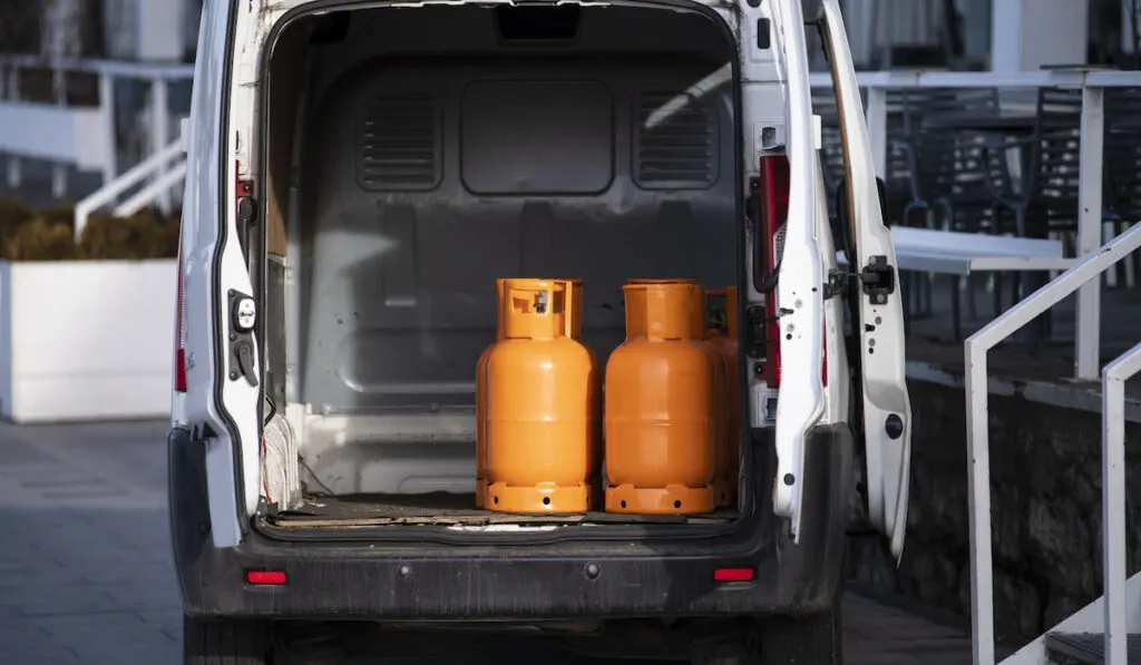 Orange gas cylinders transported inside a pickup car.