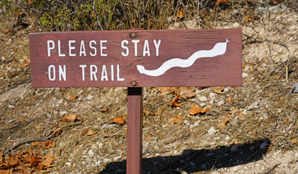 Sign warning hikers to stay on trail because of snakes 