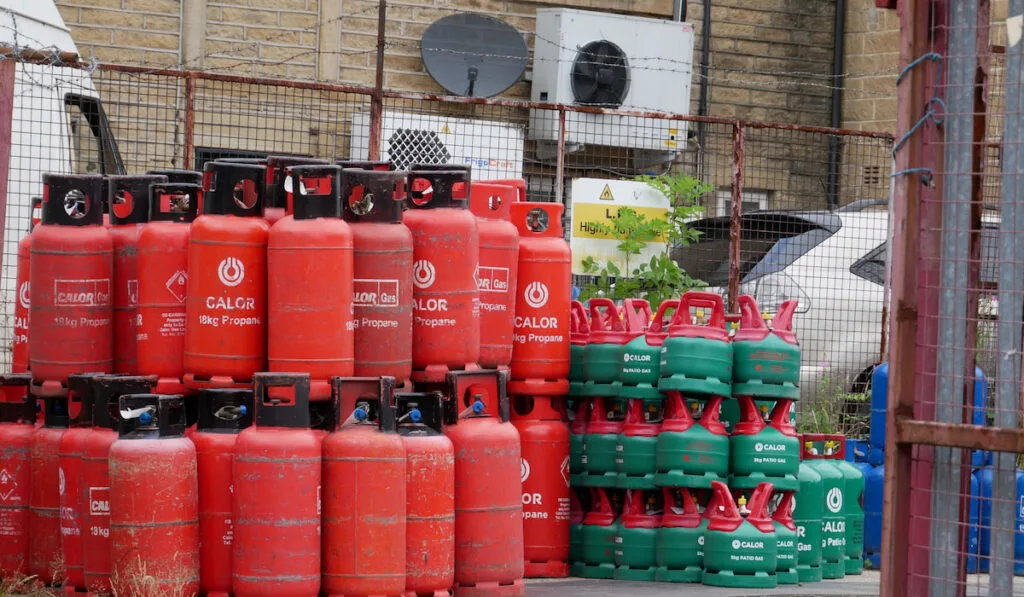 Stack of red green and blue propane gas tanks outside a shop
