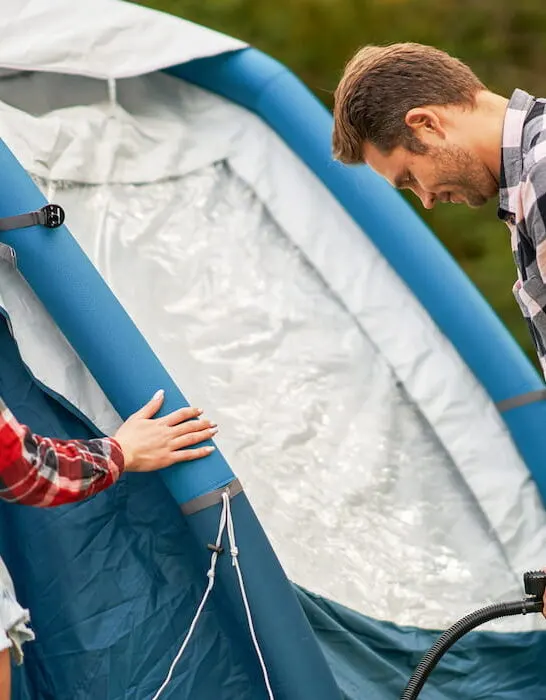 Young-couple-having-fun-on-camping-setting-up-tent
