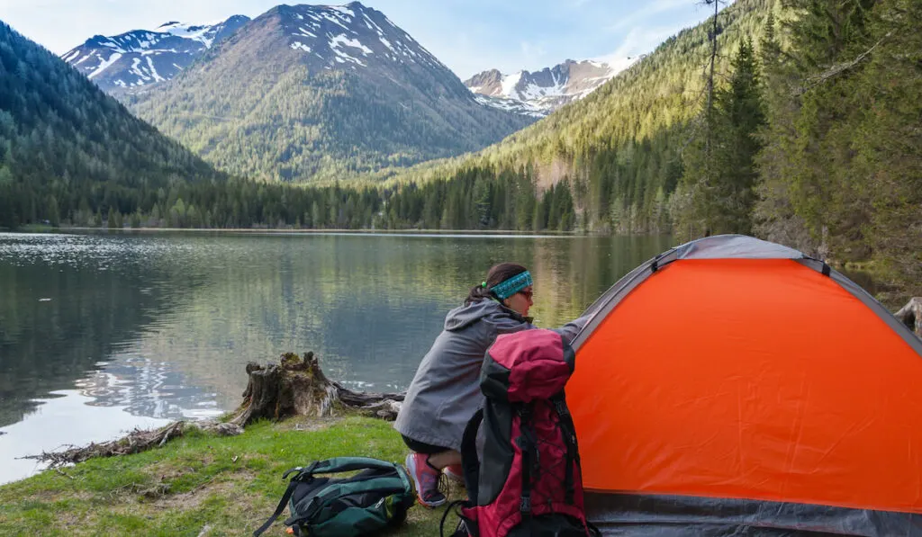 camper setting up her tent, Camp in the mountains near of the lake 