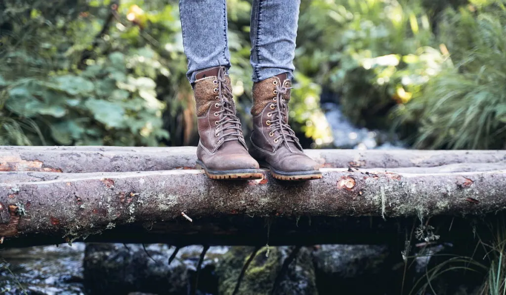 closeup of woman hiking boots on wooden bridge in the woods
