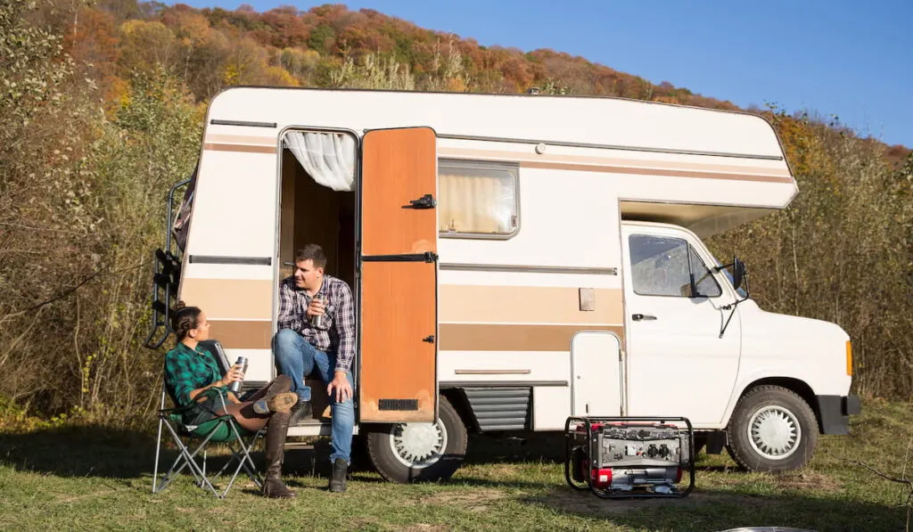 couple sitting in the retro camper van in the mountains