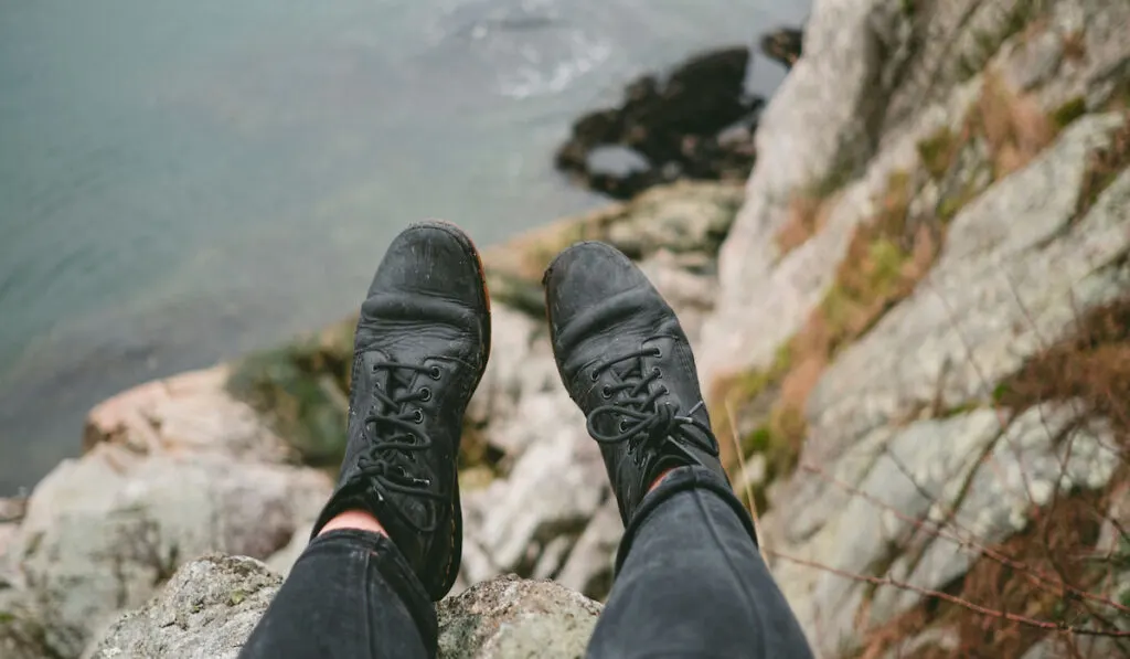 cropped shot of woman wearing doc martens shoes on top of a mountain 