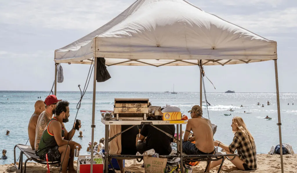 family camping near the beach sitting under a canopy 