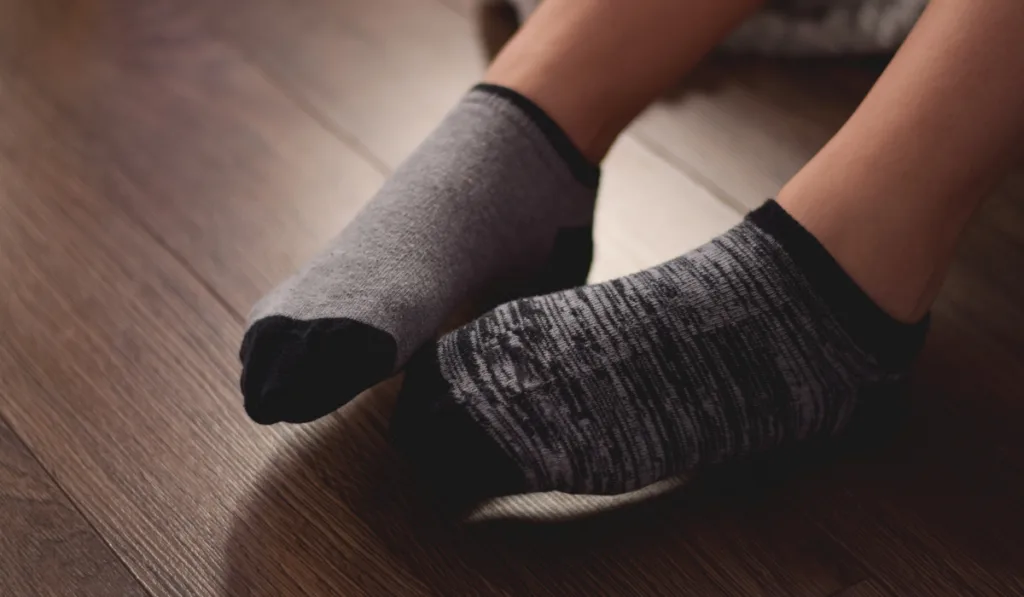 girl-sitting-on-her-bed-wearing-mismatched-ankle-socks