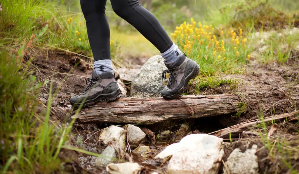 hiker in boots walking across log
