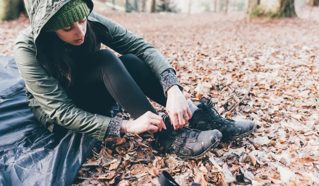 hiker putting on hiking boots in forest