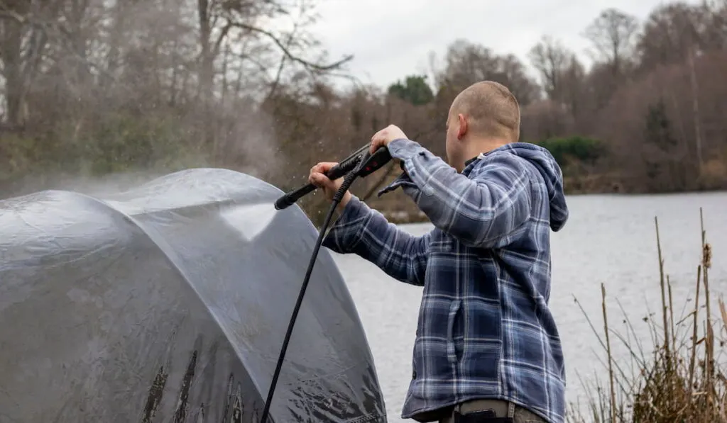 man washing  his tent near the lake