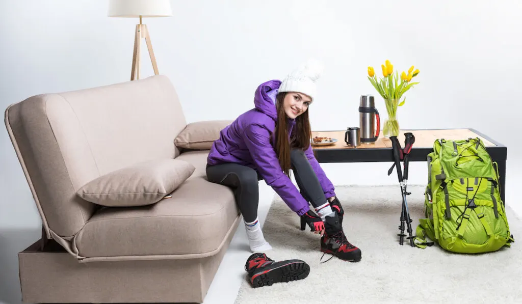 woman getting ready for a hike wearing hiking boots at home