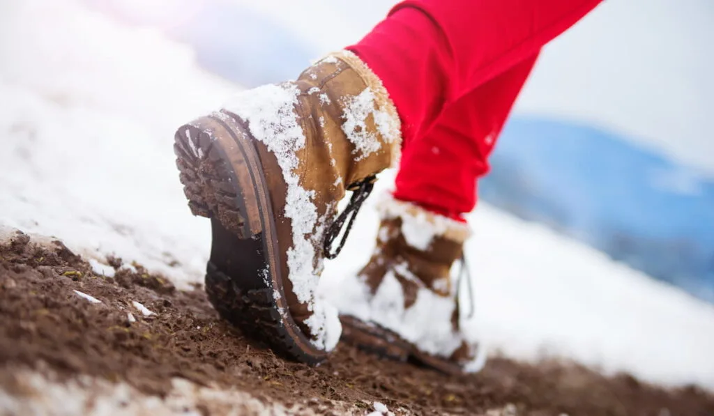 woman in red trousers and leather boots outside in snow 