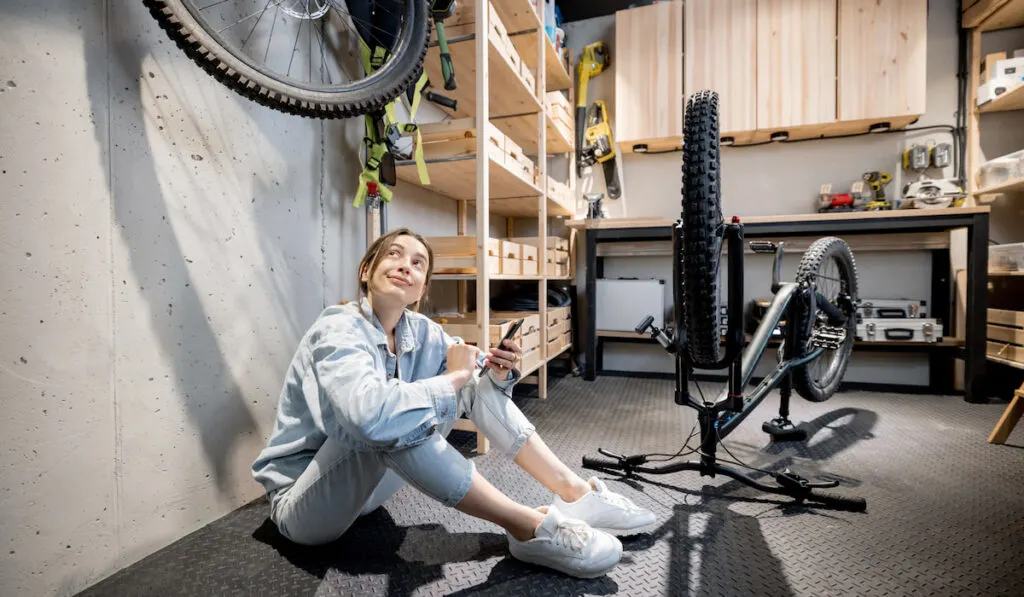 woman with phone and bicycle in the workshop at home