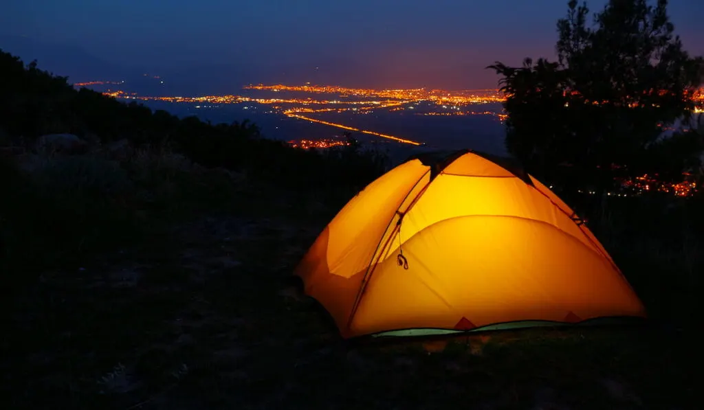 orange lighted inside tent on mountain above city