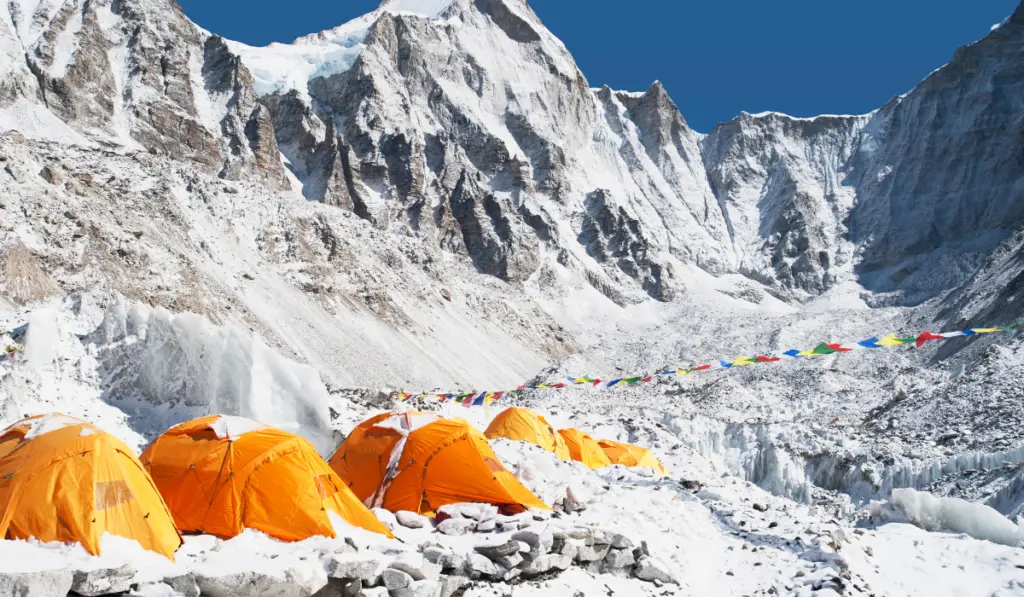 A group of orange tents at a climbers base camp in the Himalayas region