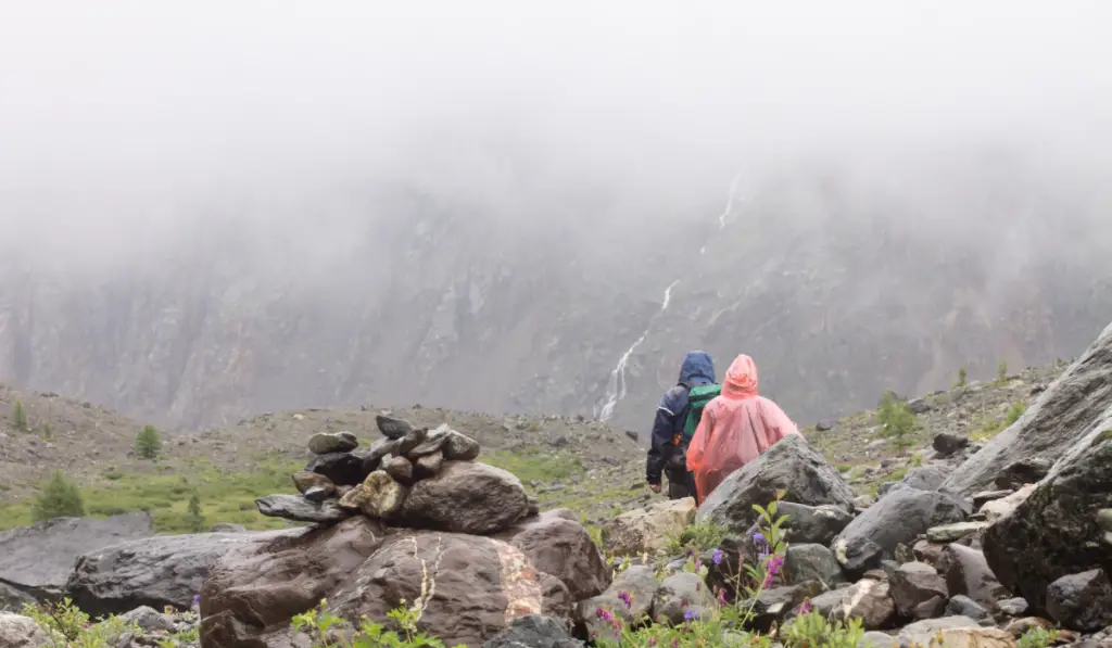 Group of people, tourists hiking in mountains. Rainy day and fog in summer time.