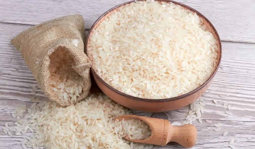 Rice in wooden bowl and wooden spoon on wooden table