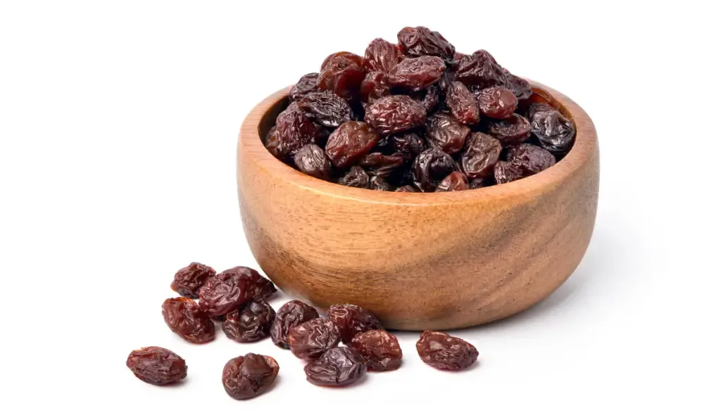 Raisins in wooden bowl isolated on white background.
