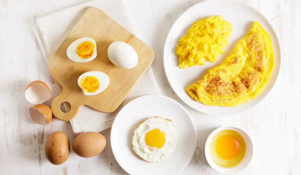 Cooking eggs in deferent way like boiled egg, fried egg and scrambled egg on wooden table